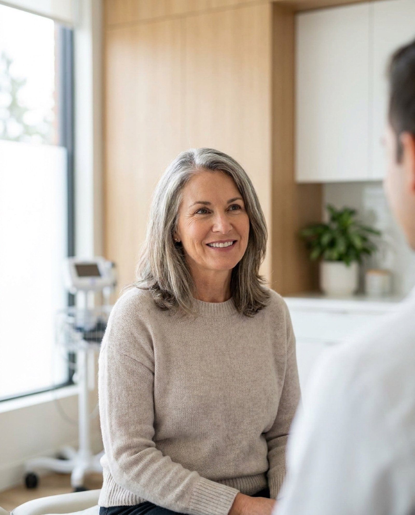Vitalis Clinic patient smiling confidently during her consultation in a modern exam room